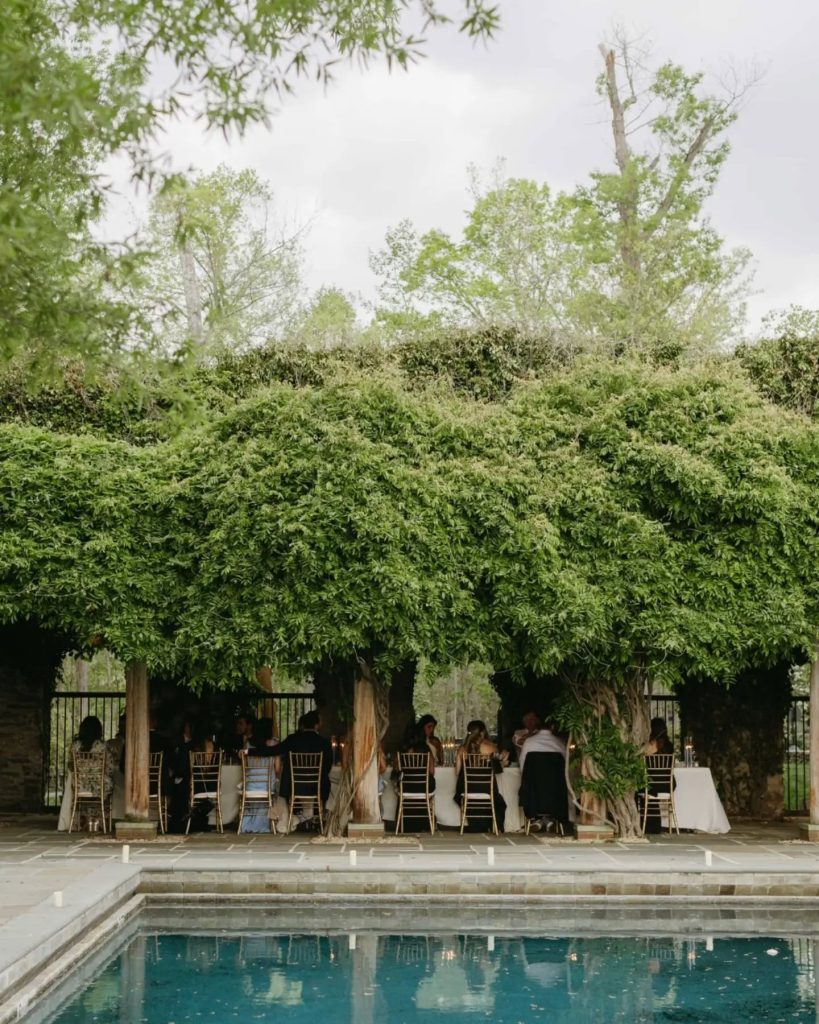 poolside wedding reception with guests under wooded covering at luxury wedding venue inspiration