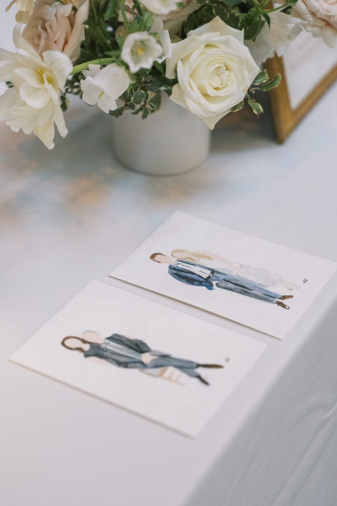 Hand-painted watercolor wedding guest portraits displayed beside an elegant white floral arrangement, showcasing personalized live wedding artwork at a Columbus, Ohio wedding.