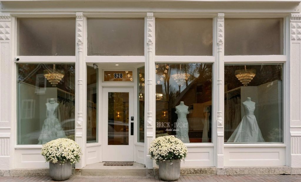 Exterior of Brick + Ivory Bridal Studio with wedding gowns displayed in its storefront windows.