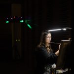 Live wedding painter creating a custom portrait during a dimly lit reception.