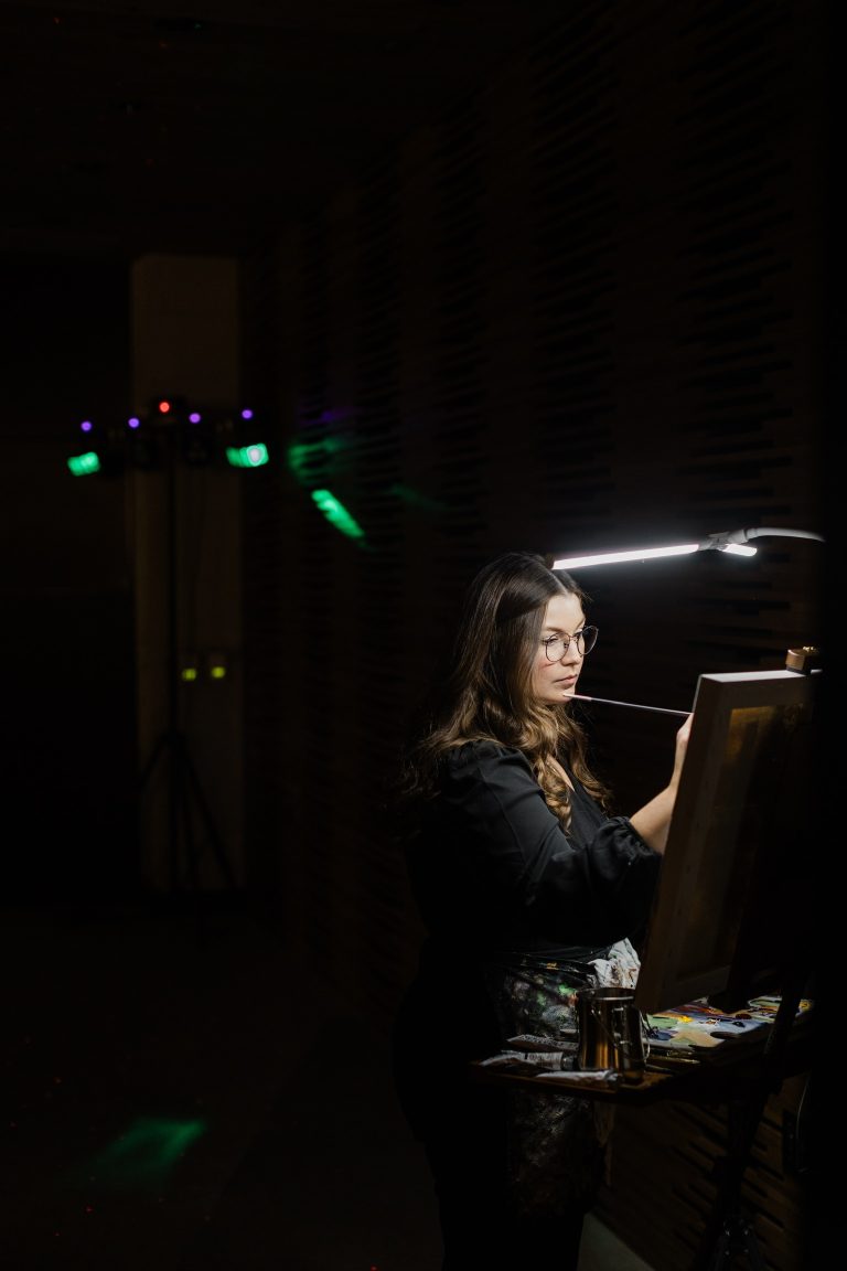 Live wedding painter creating a custom portrait during a dimly lit reception.