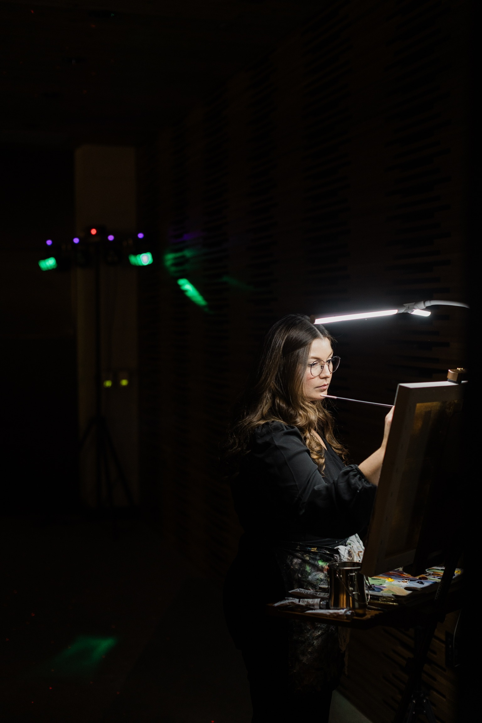 Live wedding painter creating a custom portrait during a dimly lit reception.