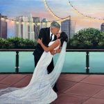 Hand-painted wedding portrait of a couple kissing on a rooftop terrace beneath string lights and a city skyline.