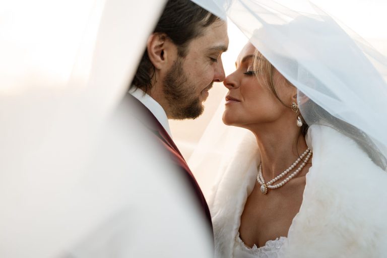 Bride and groom embracing under veil. Bridal makeup and hair done by LUX Studio.