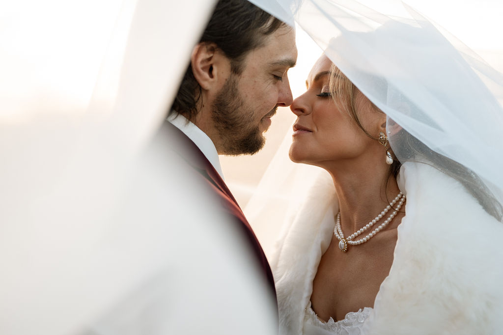 Bride and groom embracing under veil. Bridal makeup and hair done by LUX Studio.