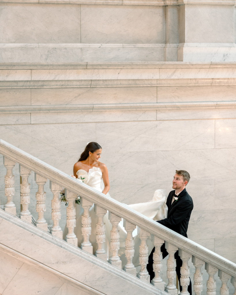 Jane and Kevin pose together on a grand marble staircase during their romantic Columbus wedding.