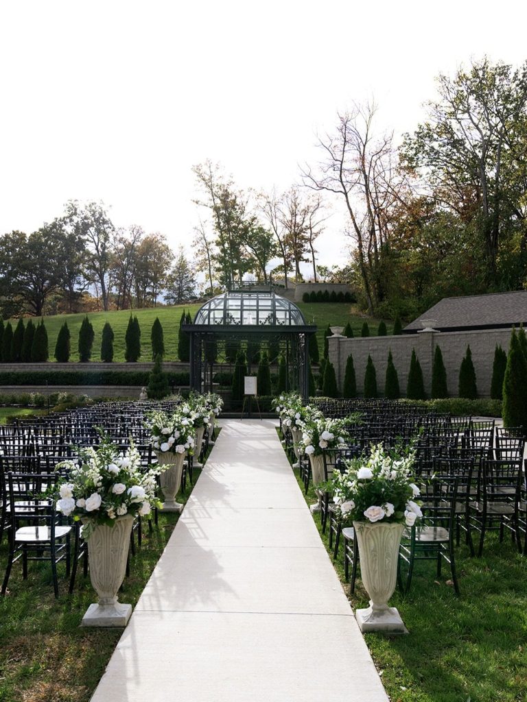 Outdoor wedding ceremony at Knotting Hills with aisle lined with florals.
