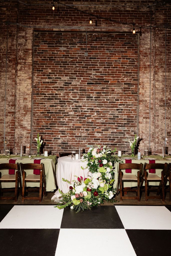 Sweat heart table with cascading florals stopping on black and white checkered dance floor from Gracie Marie's Florals.