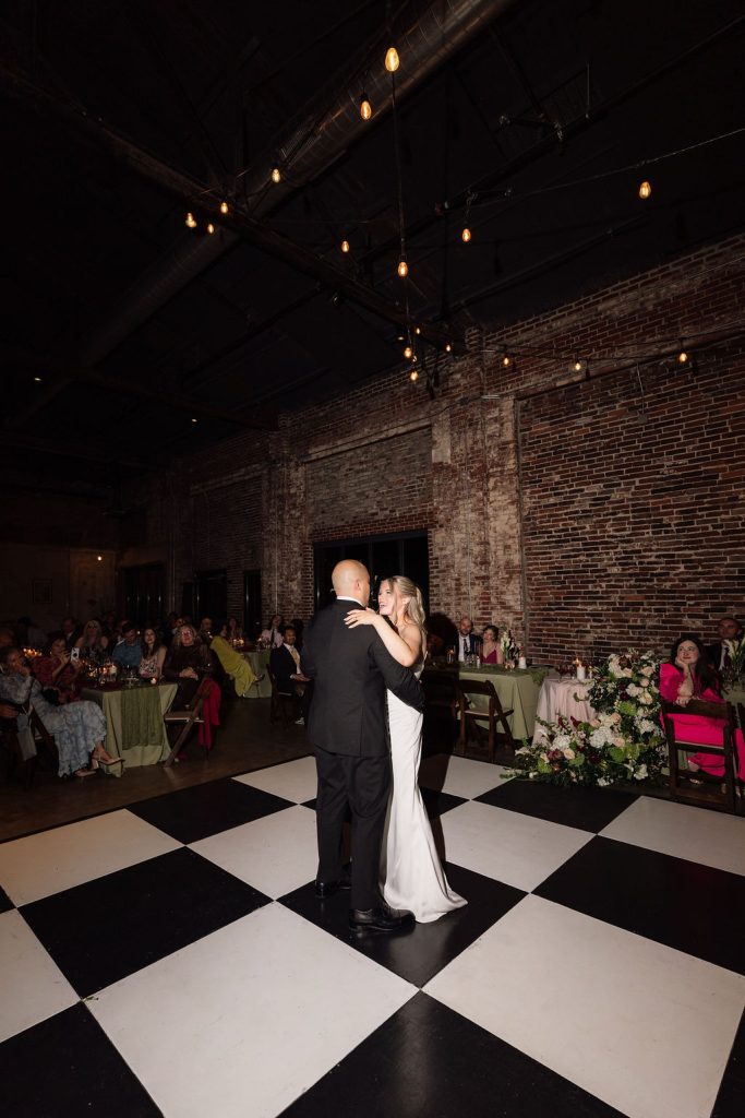 Bride and groom dancing on black and white checkered dance floor from Gracie Marie's Florals.