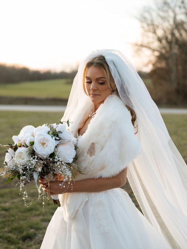 Bride posing with an all white bridal bouquet with makeup and hair by LUX Studio.