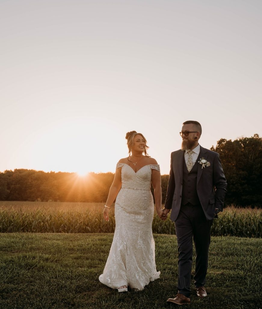 bride and groom walking in golden hour away from sunset on farm