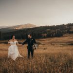 bride and groom running through prairie with mountains in the background, warm editing style photographer northern virginia