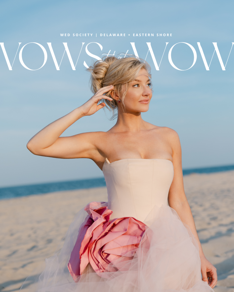 Bride in a blush pink wedding gown with oversized magenta flower detail on the beach in Rehoboth Beach, Delaware.
