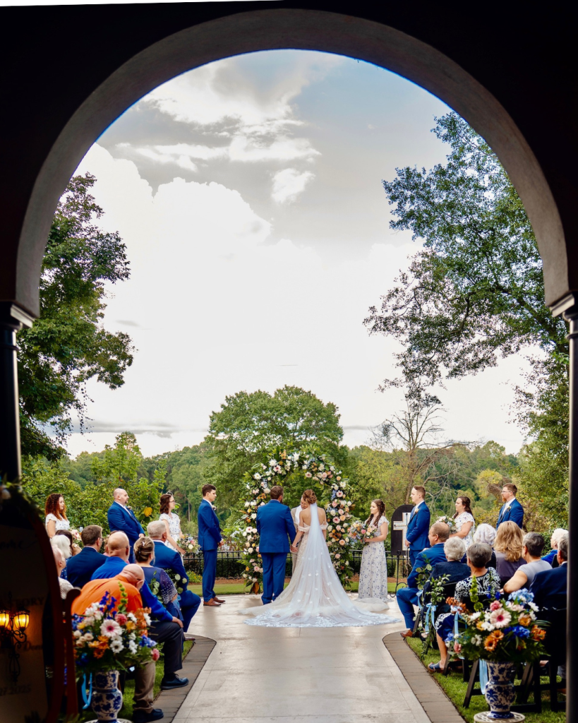 Outdoor wedding ceremony at The Riverwalk Event Venue with floral ceremony arch, guests seated, and scenic landscape views in Rock Hill, South Carolina.