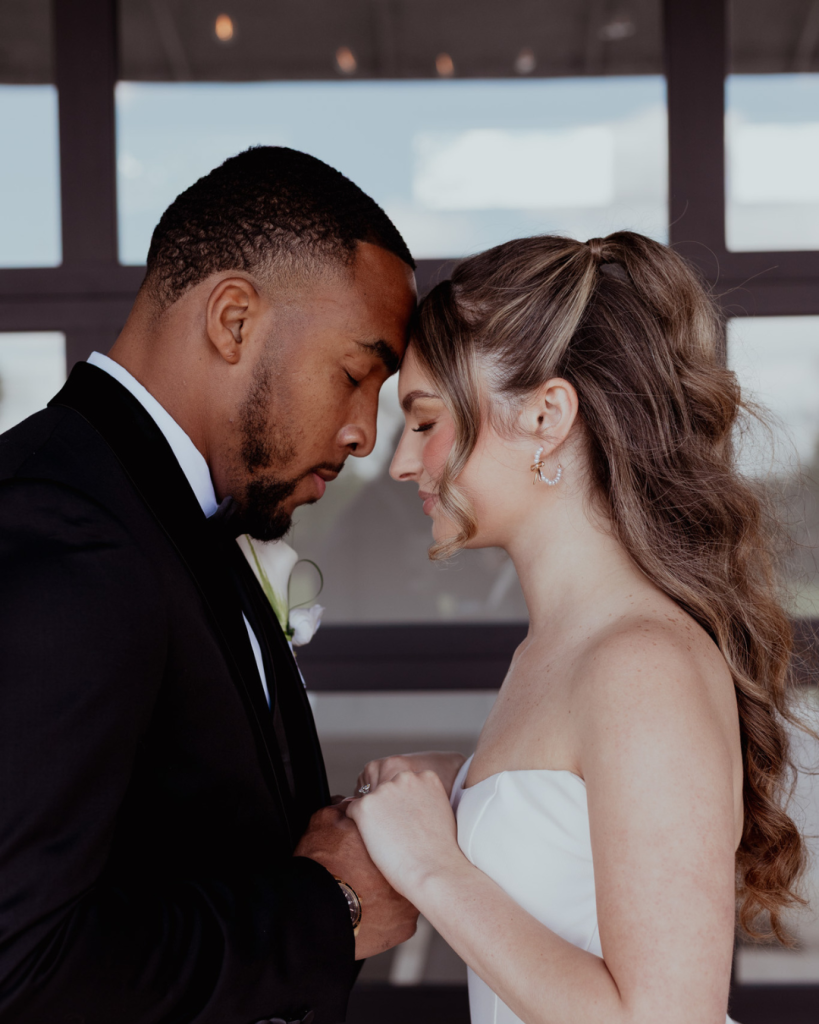 TreVeyon and Kenzie hold hands and rest their foreheads together during a quiet wedding-day moment.