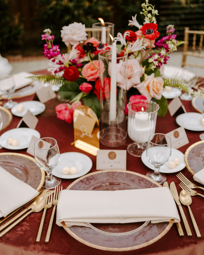 Romantic reception centerpiece with colorful flowers, candles, gold flatware, and blush velvet linen at a Charlotte wedding featured by Wed Society Charlotte.