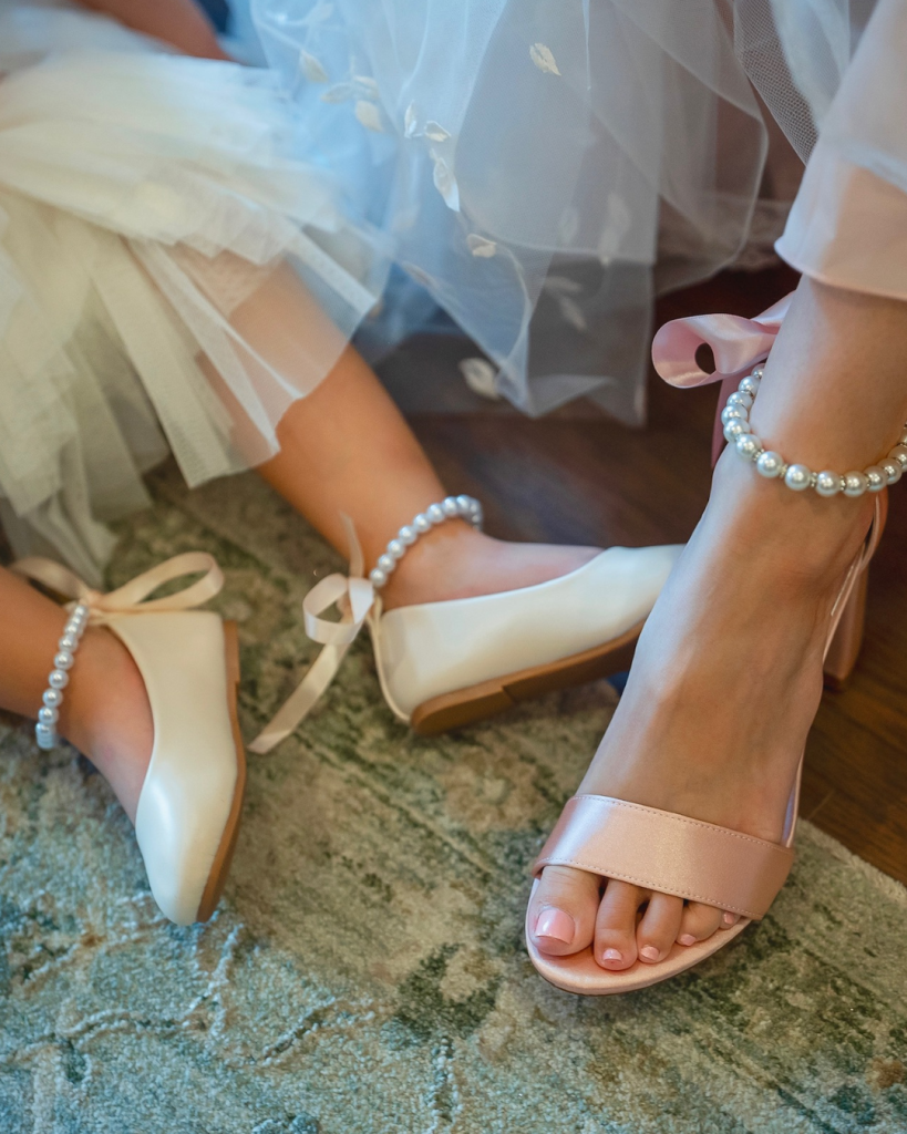 Bridal shoes with pearl ankle straps and soft pink ribbon details photographed during getting ready.