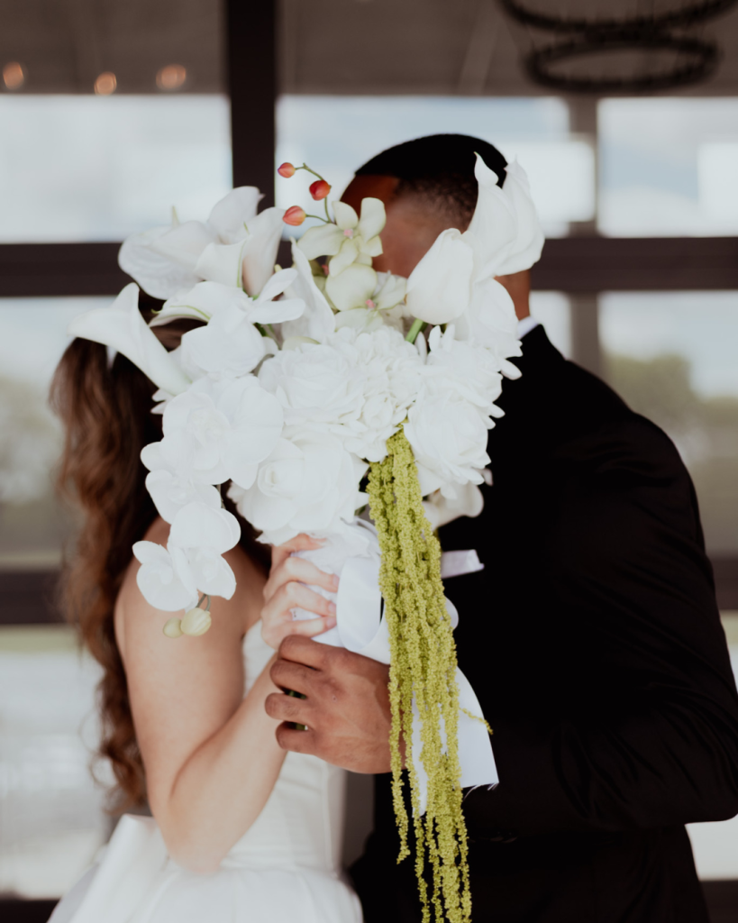 TreVeyon and Kenzie embrace behind Kenzie’s cascading white bouquet inside Twin Run Farm.