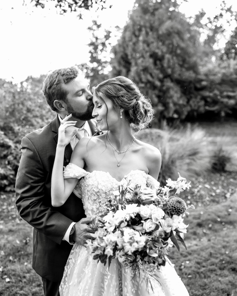 Black and white portrait of the bride and groom embracing outdoors with colorful bouquet at The Riverwalk Event Venue.