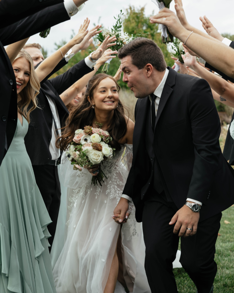 Abigail and Joel walk beneath an arch formed by their wedding party after their Retreat 21 ceremony.