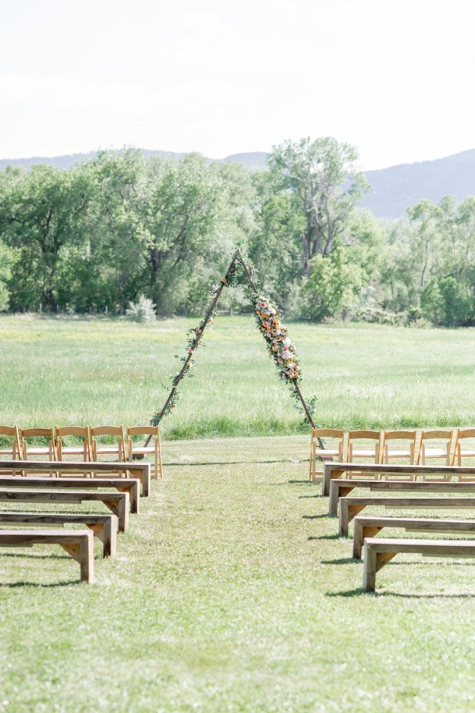 Outdoor ceremony with triangle arch and flowers