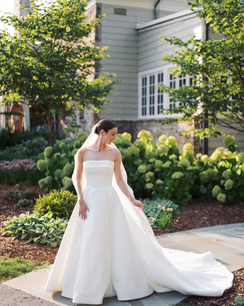 Caroline poses in a strapless white ball gown and lace veil in a sunlit garden before her Columbus wedding.