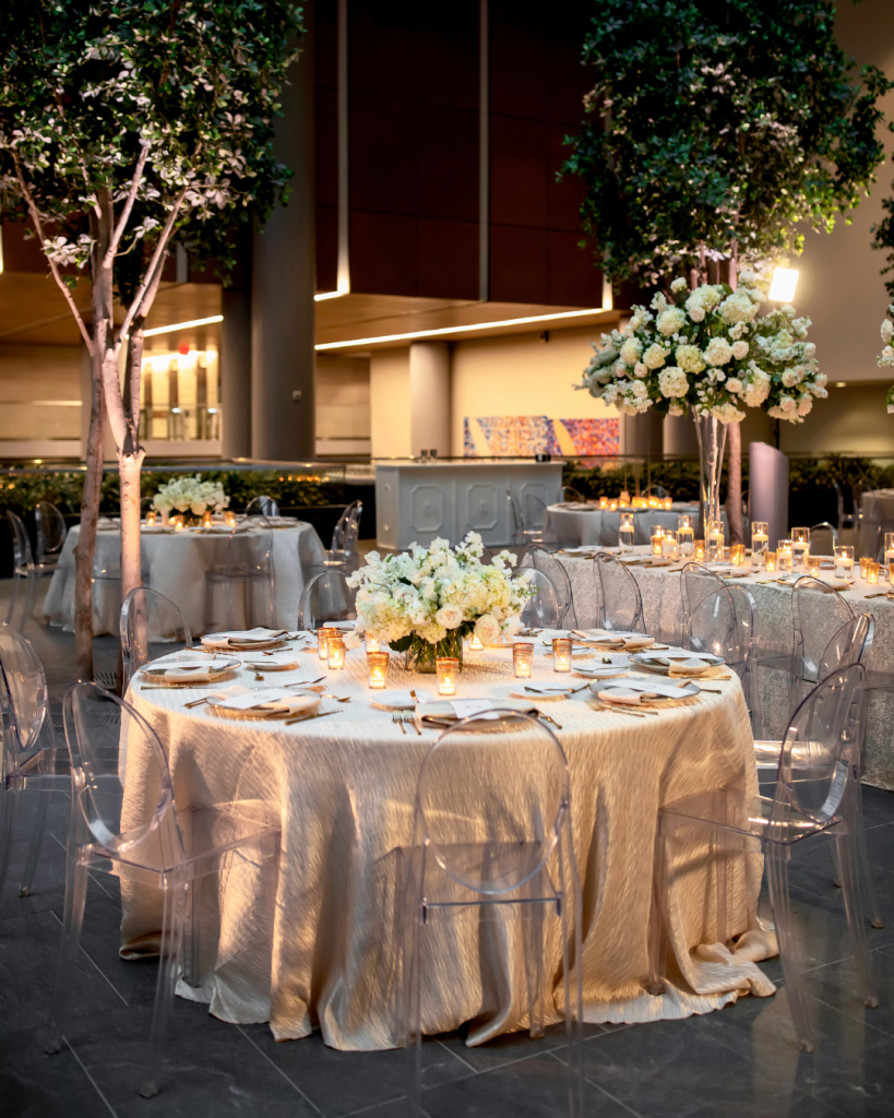 Luxury wedding reception table at The Ritz Carlton Charlotte featuring white florals, candlelight, clear chairs and textured ivory linens.
