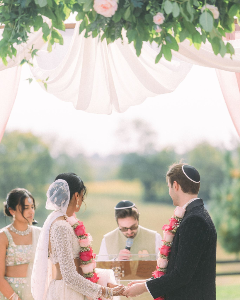 south asian wedding ceremony with flower necklaces, holding hands, outdoor wedding ceremony in northern virginia