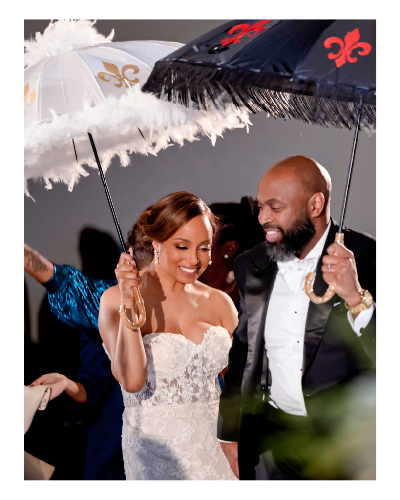 Joy and Edward celebrate beneath second line umbrellas, incorporating Edward’s Louisiana roots into their wedding reception.