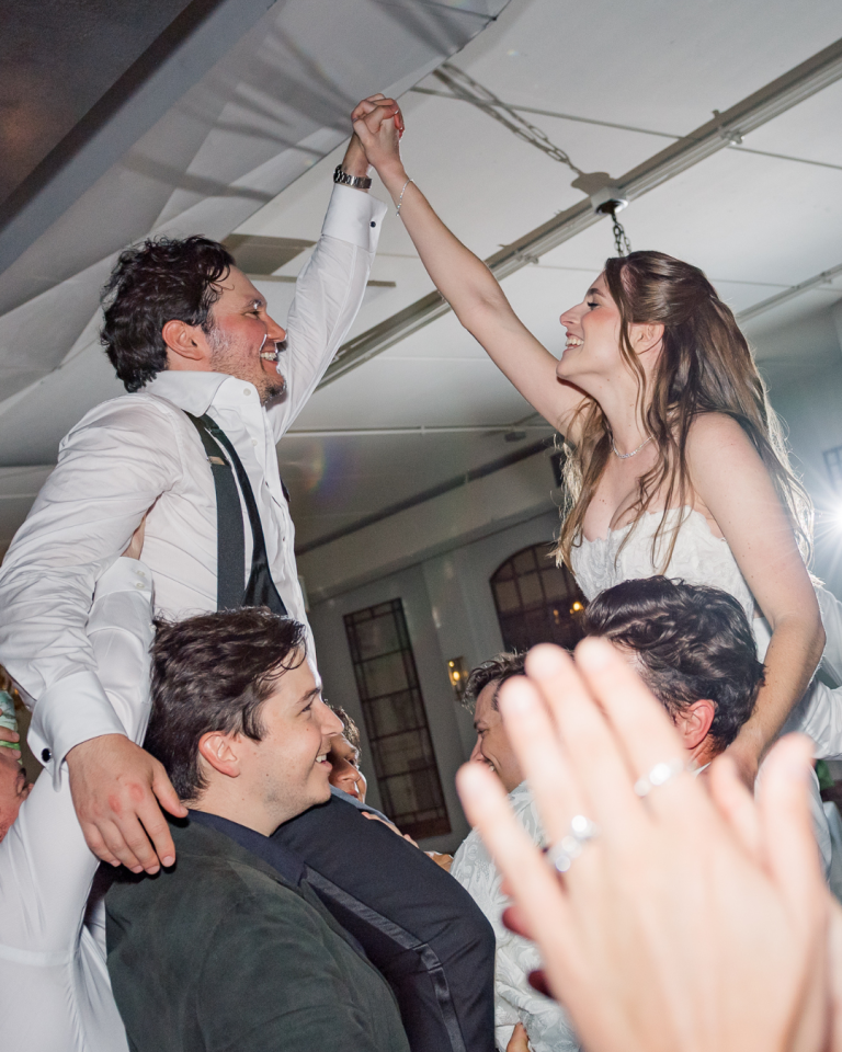 bride and groom cheering at wedding lifted up at wedding reception