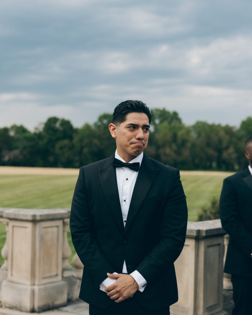 groom looking at bride as she walks down the wedding aisle