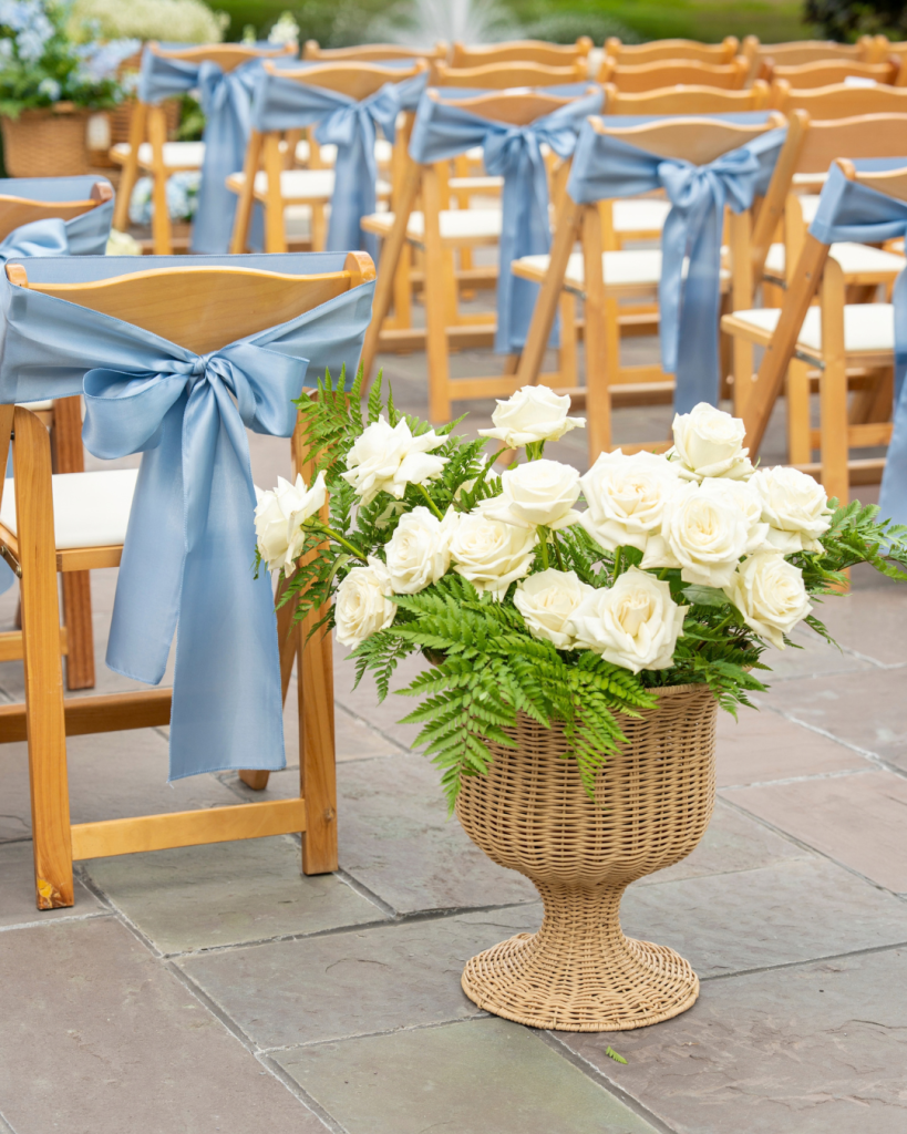 white roses in a wicker basket lining wedding aisle