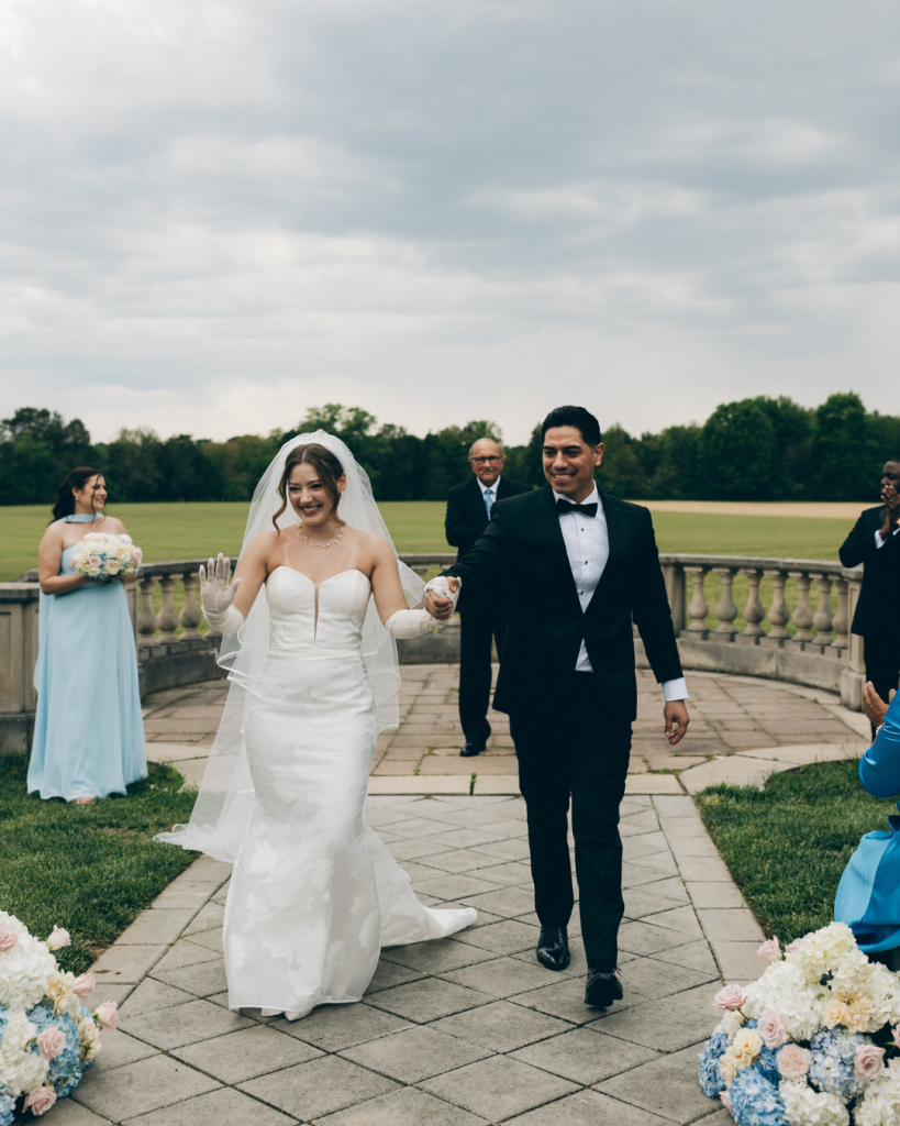 bride and groom walking out of wedding ceremony holding hands smiling together