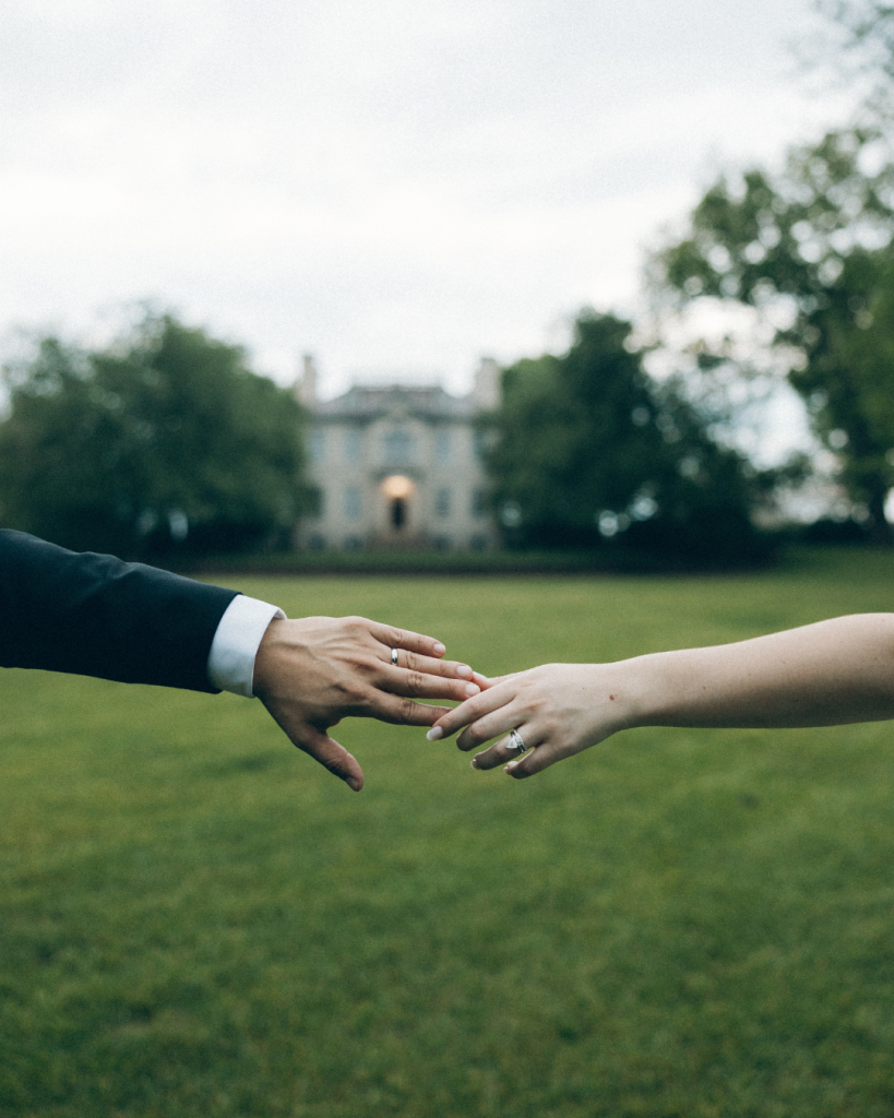 hands touching in front of blurred background of wedding venue