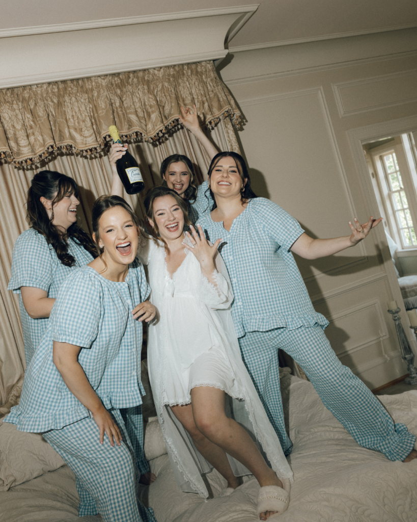 bride and bridesmaid in light blue getting ready morning of wedding day singing laughing together