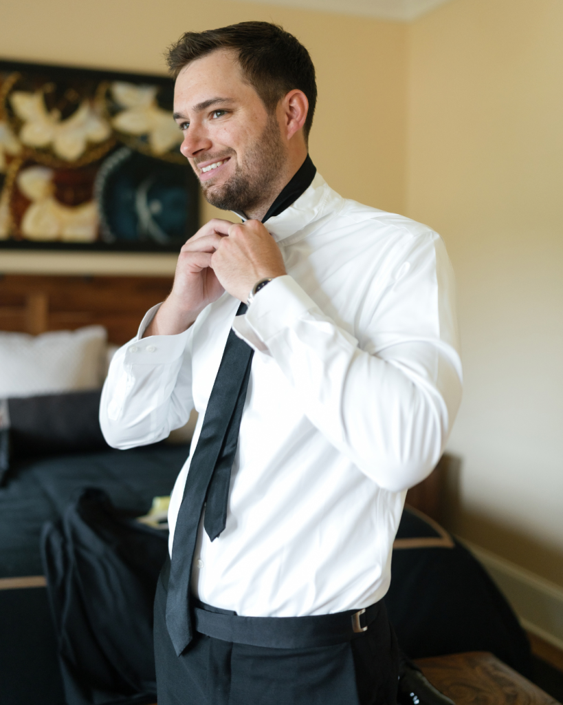 Groom Peyton adjusts his black tie while getting ready for his wedding day in North Carolina.