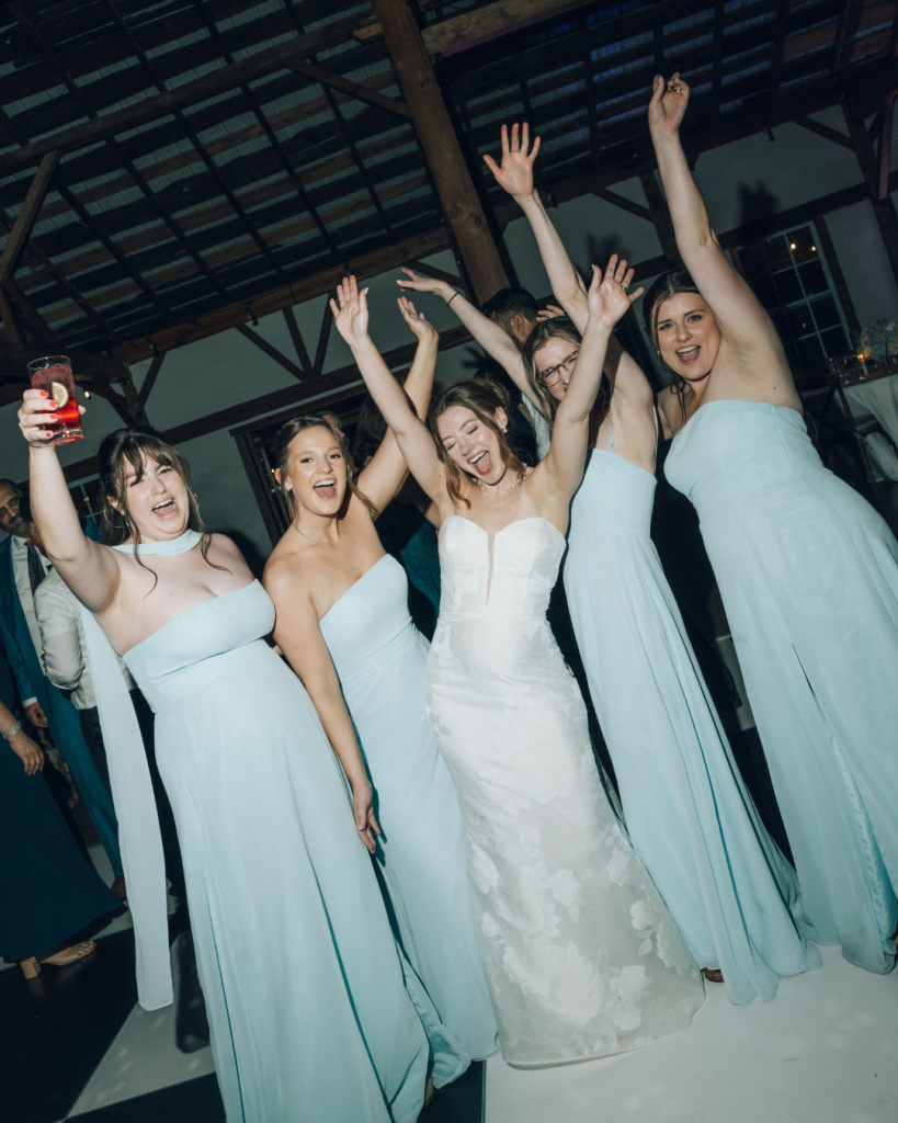 bride with bridesmaid in blue dress cheering during wedding reception