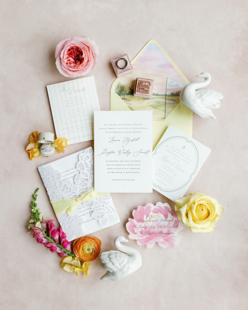 Lauren and Peyton’s colorful wedding invitation suite styled with rings, flowers, yellow accents and swan details.