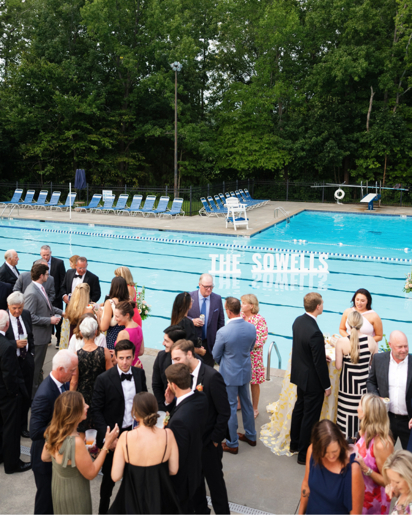 Guests gather beside the pool at Pine Lake Country Club during Lauren and Peyton’s colorful summer wedding reception.