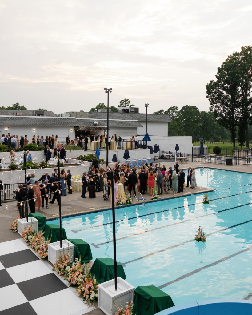 Guests gather around the pool at Pine Lake Country Club for Lauren and Peyton’s outdoor summer wedding reception.