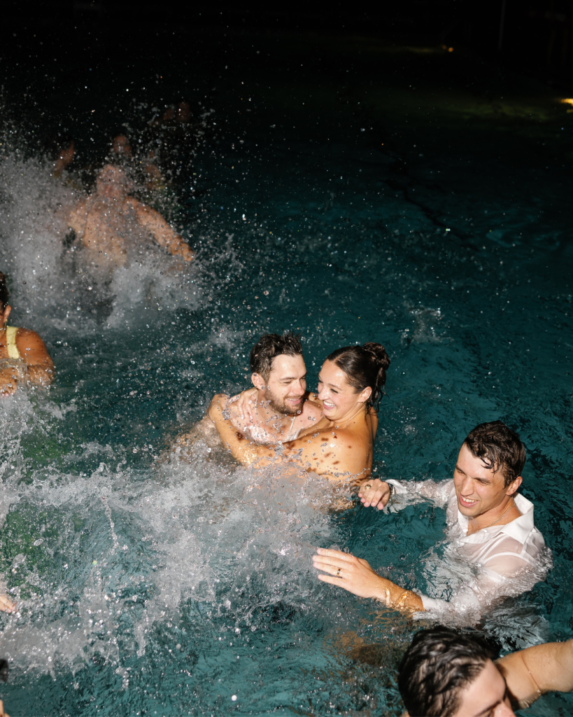 Lauren and Peyton celebrate in the swimming pool with friends at the end of their Pine Lake Country Club wedding reception.