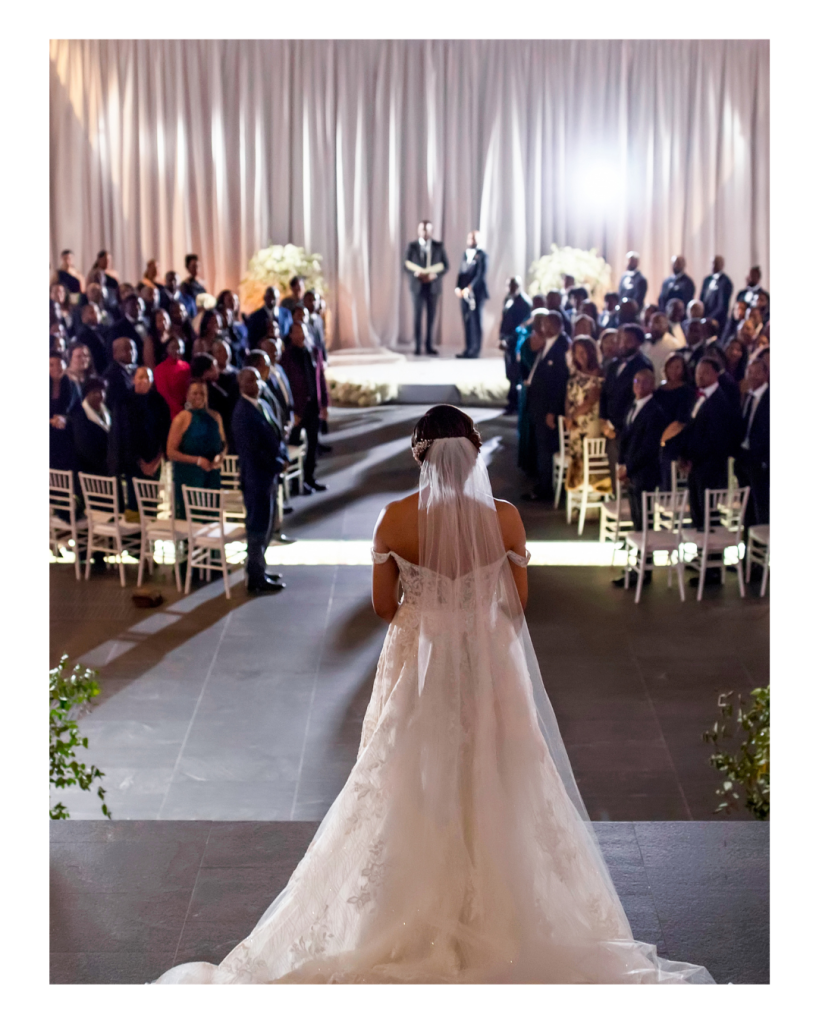 Joy walks down the aisle toward Edward during their indoor ceremony at The Ritz Carlton Charlotte in Charlotte, North Carolina.