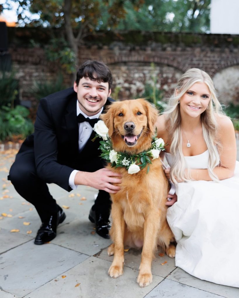 Bride and groom with their golden retriever wearing a white floral collar at Gadsden House wedding in Charleston