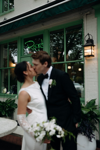 Bride and groom kissing in front of building. true to color editing photography style