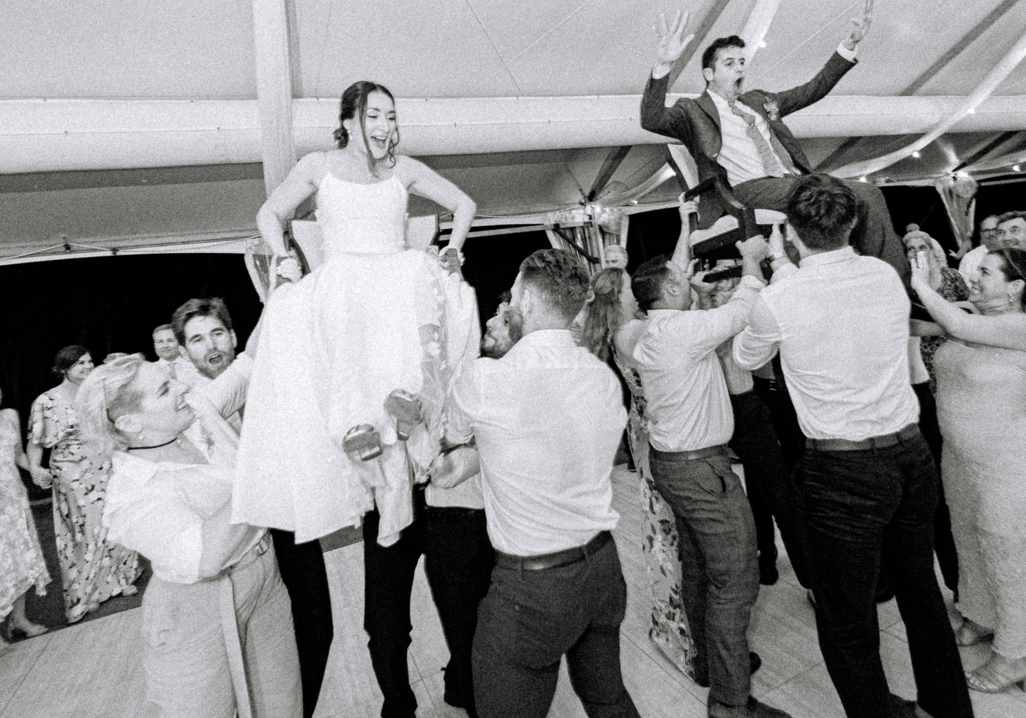 Black-and-white collage of the bride and groom lifted in chairs during the hora at their tented Kent Island Resort wedding reception in Stevensville, Maryland.