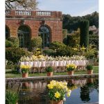 Outdoor wedding reception setup beside a reflecting pool and brick building.