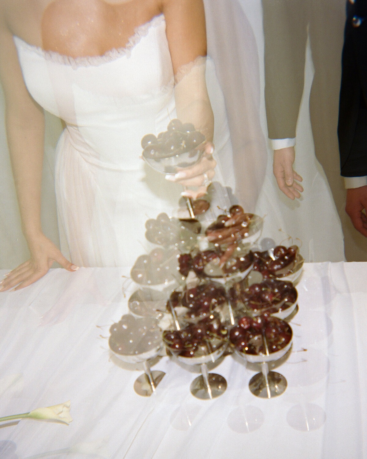Bride pouring champagne into a tower of coupe glasses.