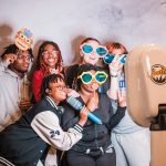 Group of guests pose with oversized glasses and playful props at a Best Booths in Town photo booth.
