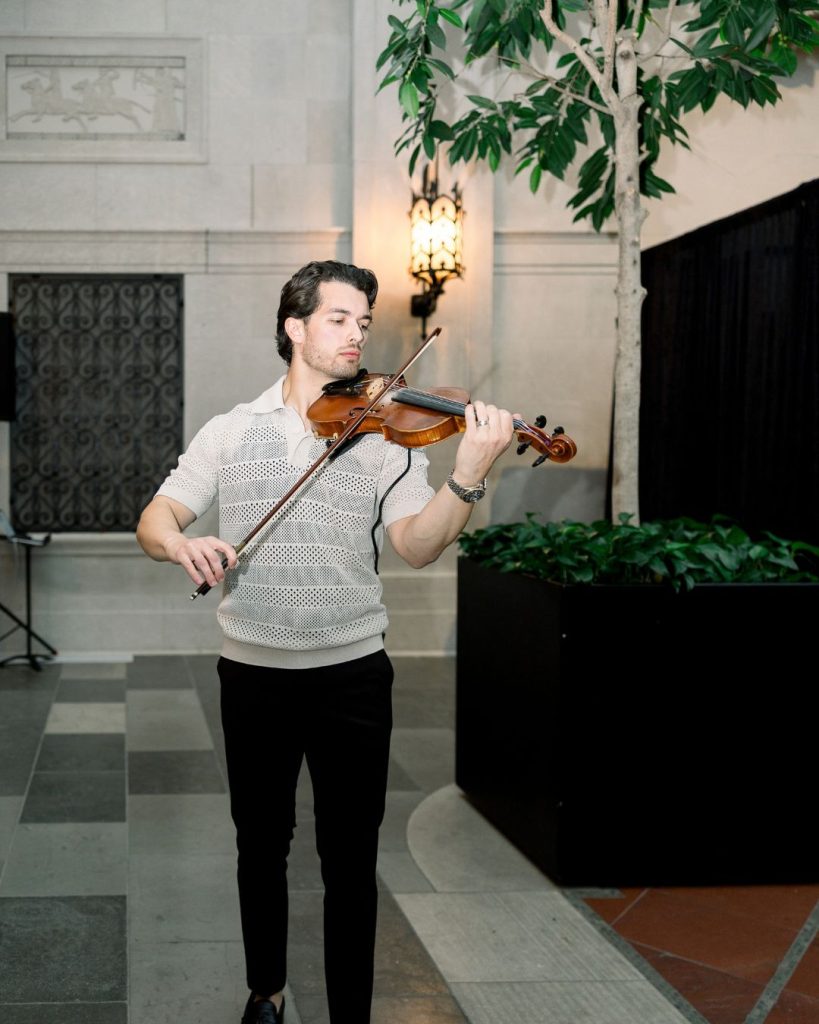 Violinist performs beside greenery and black draping at the Columbus Museum of Art release party.