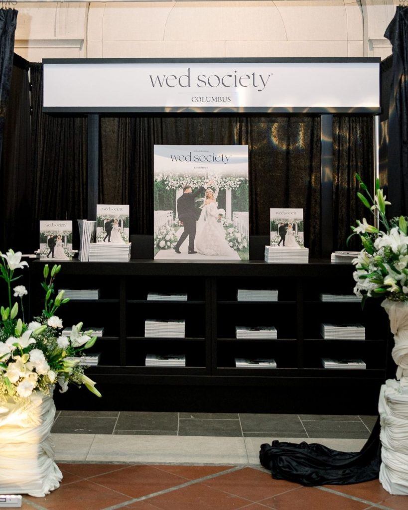 Black Wed Society Columbus magazine display surrounded by white flowers, greenery, and black draping.